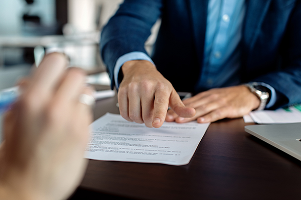 Close-up of financial advisor pointing at place of signature on